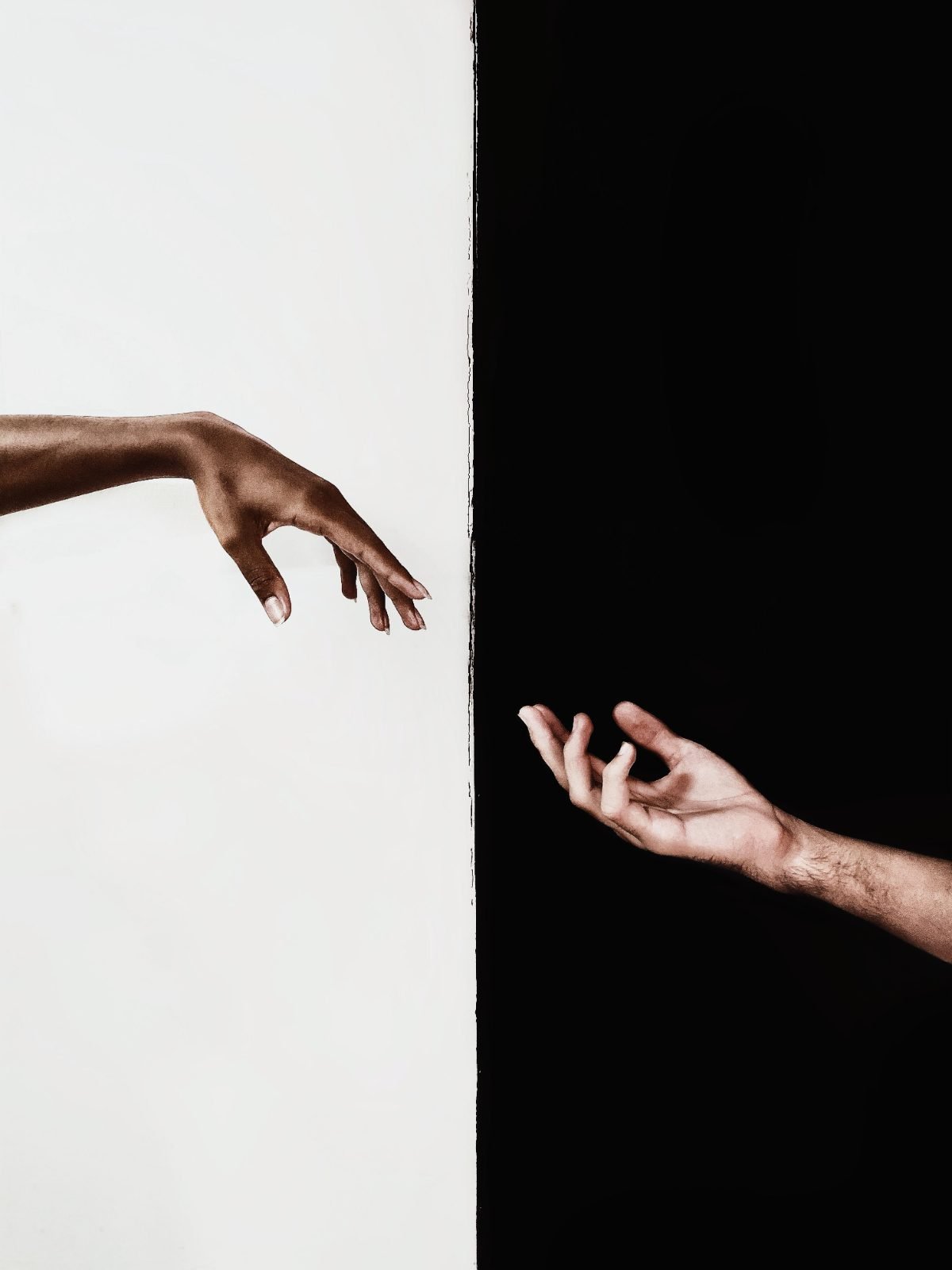 Two hands reaching across a black and white divide